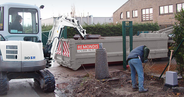Graafmachine werpt zand in container van Remondis Depoorter